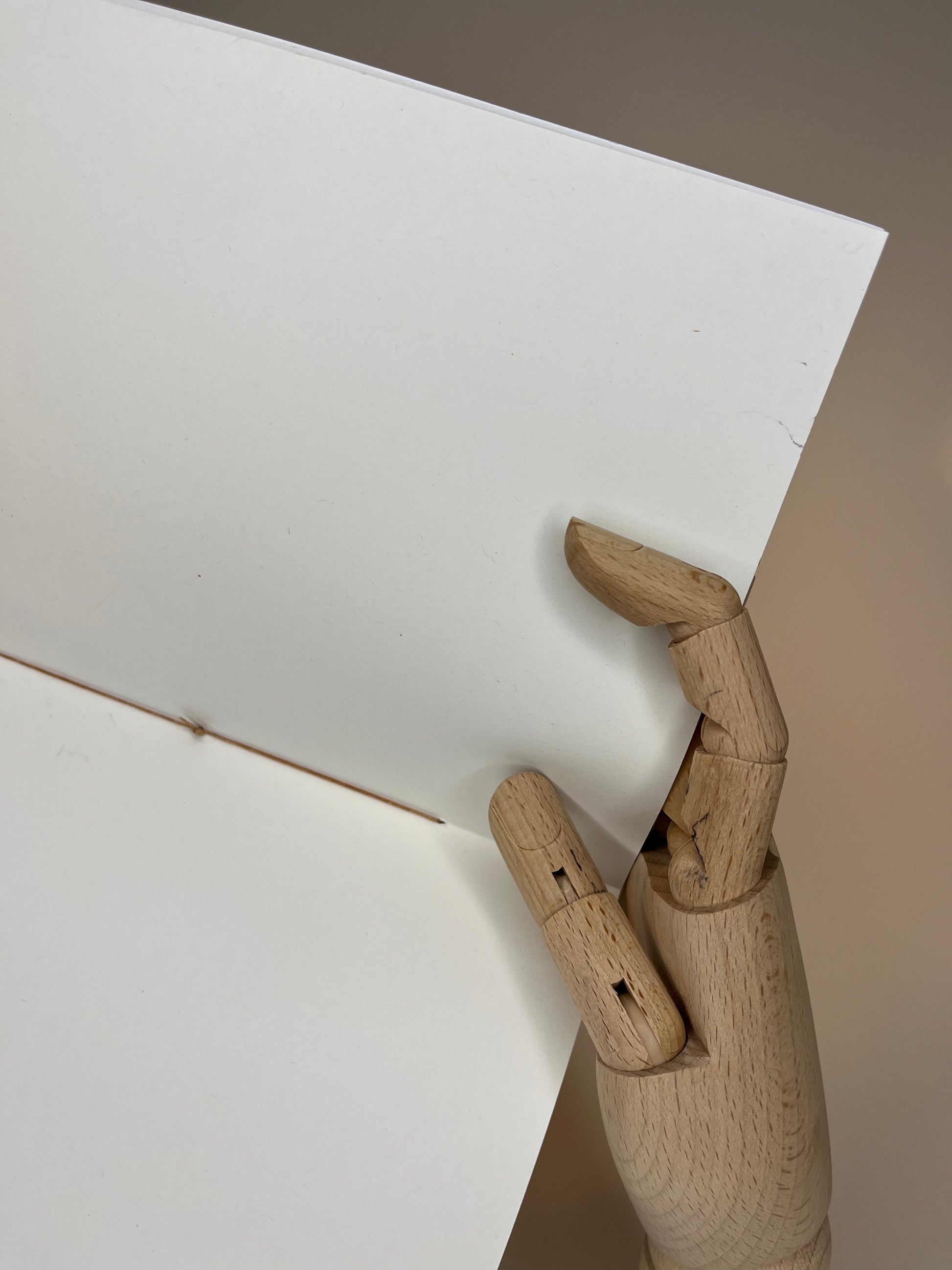 Wooden mannequin hand holding blank white paper.