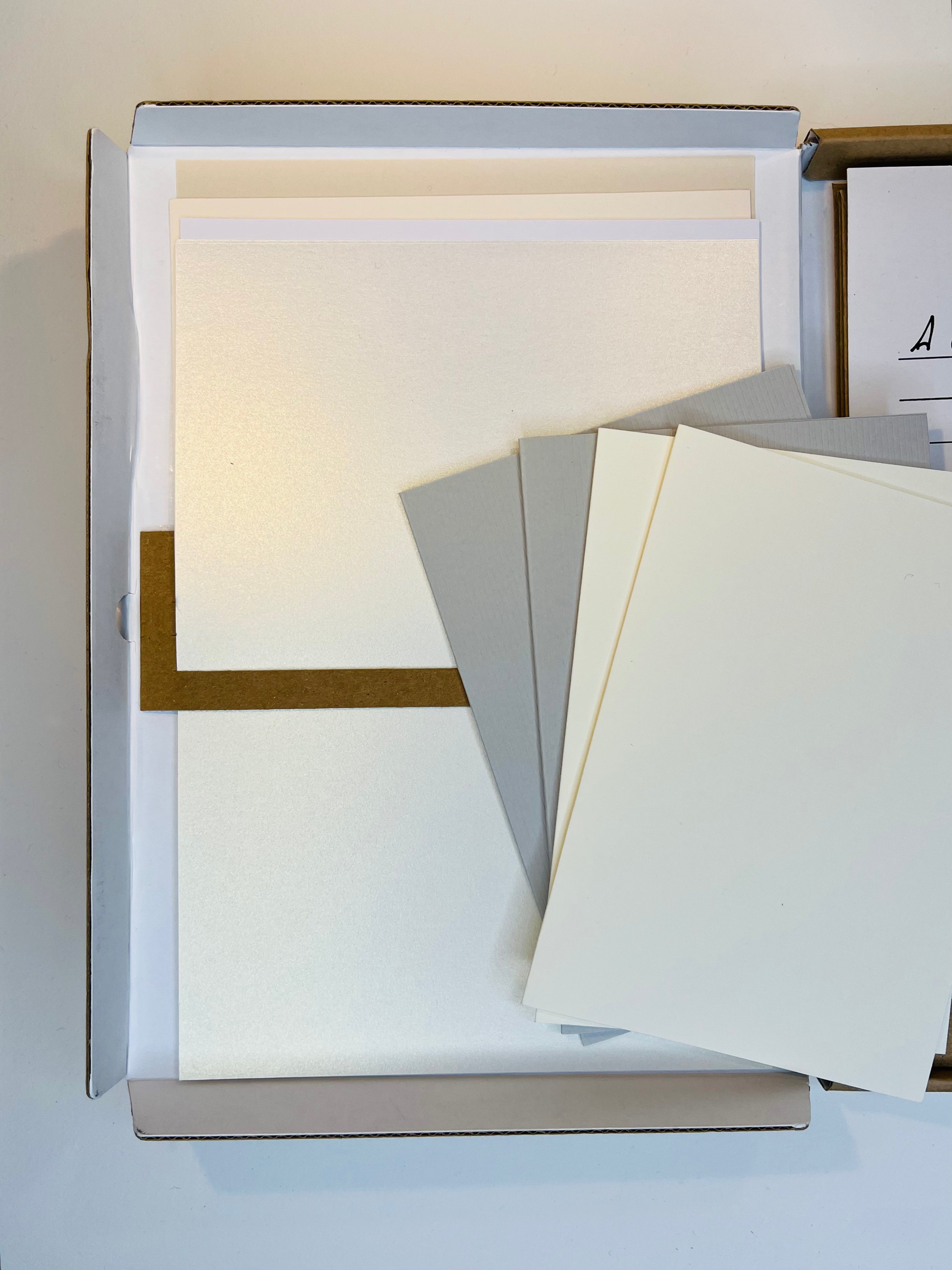 Open box of craft card stock in assorted neutral colors.