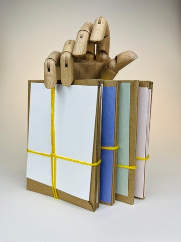 Wooden hand holding a stack of tied, colorful envelopes.