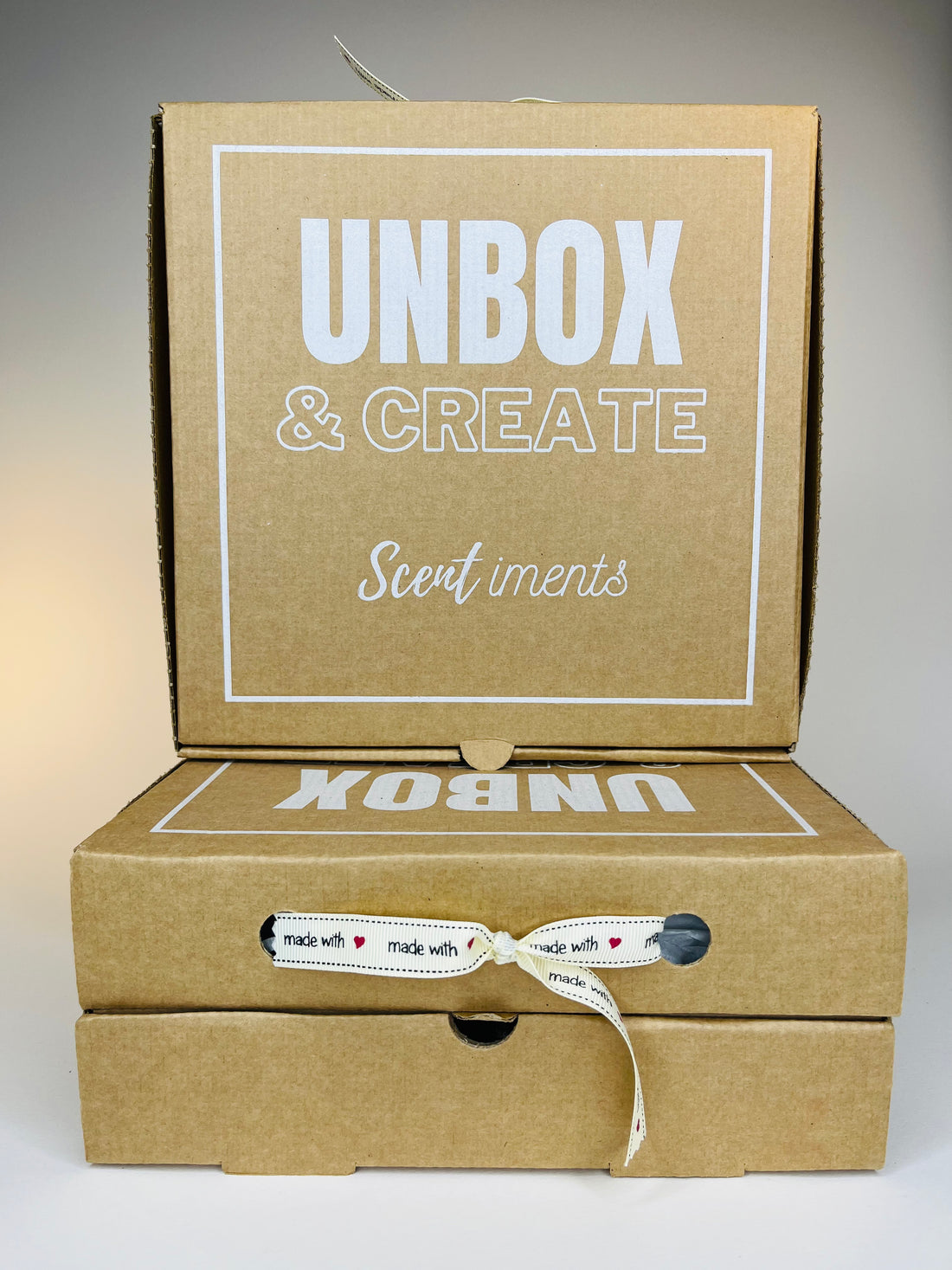 A stack of three brown cardboard boxes with white lettering and a ribbon tied around the middle box.