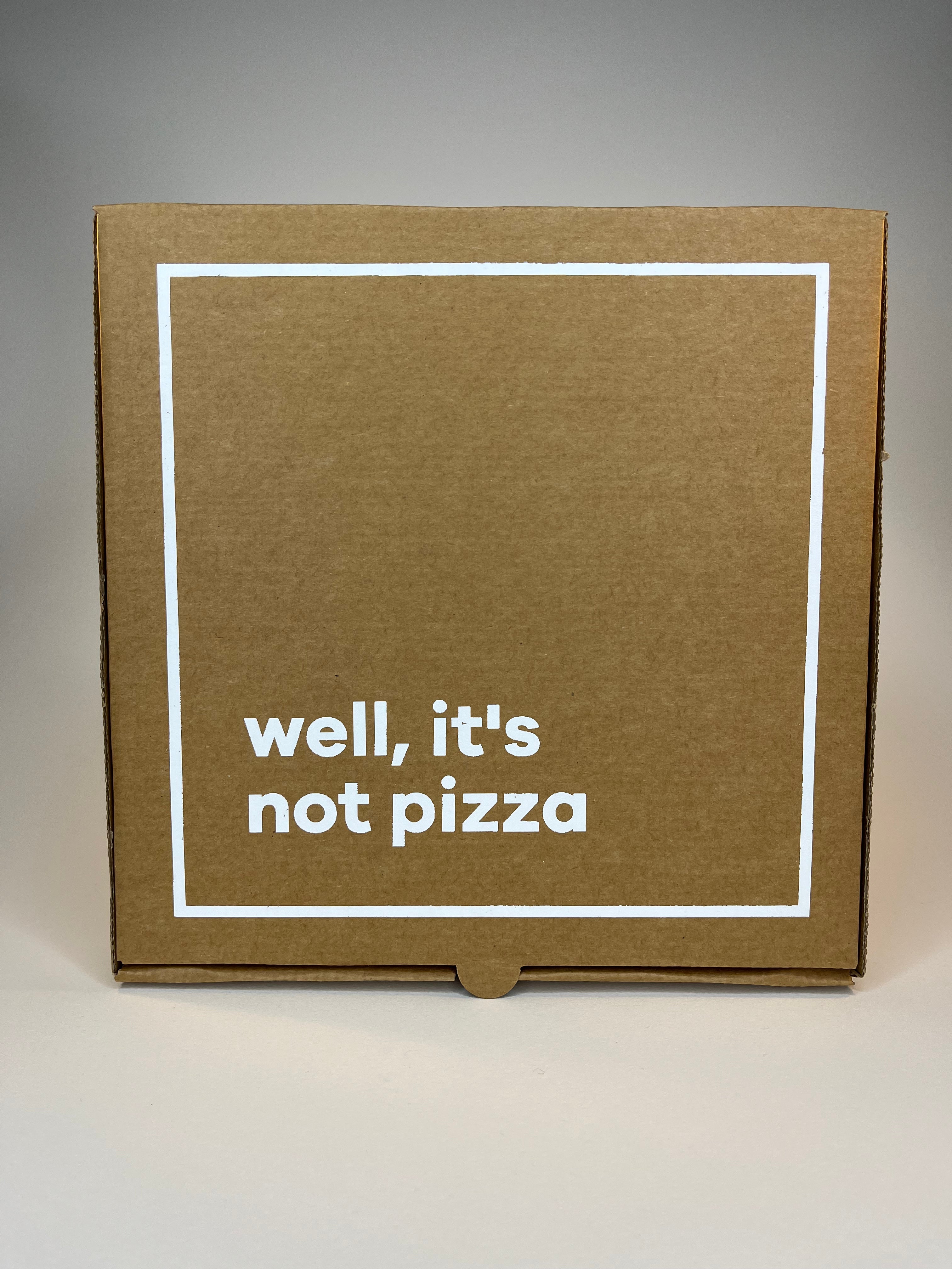 Brown cardboard box with white border and text "well, it's not pizza".