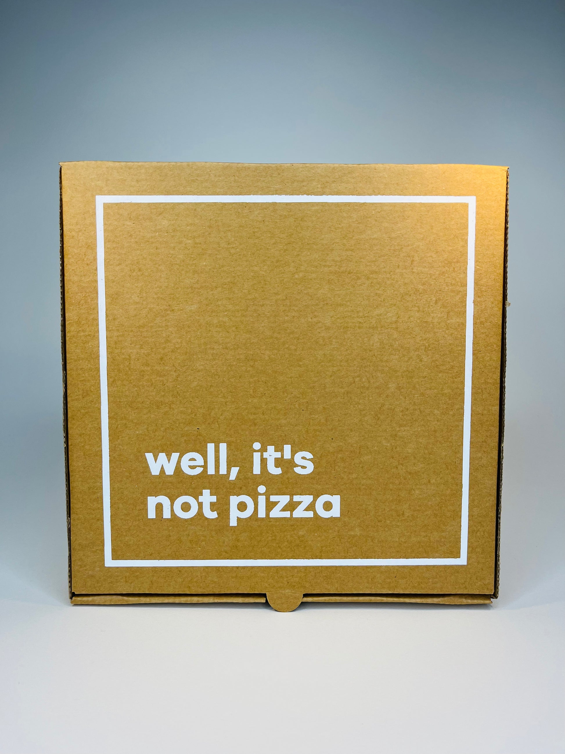 Brown cardboard box with white border and text reading "well, it's not pizza."