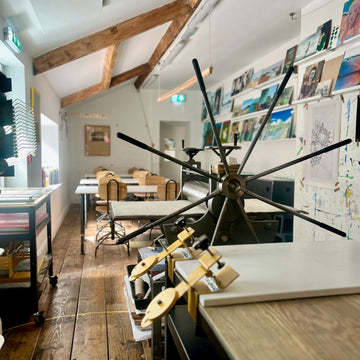 Art studio, Printing press with a steering wheel in the shape of a rudder. Long, bright, and spacious room with rustic wooden floor and beams.