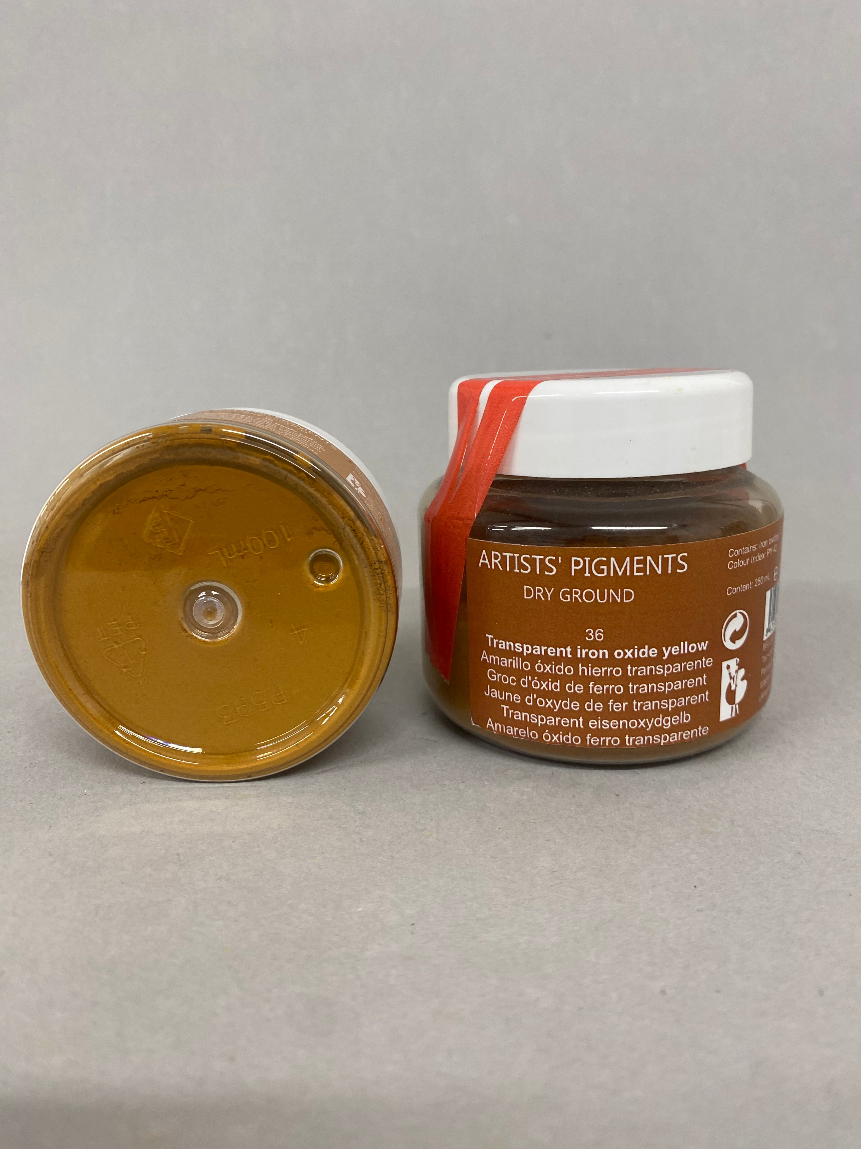 Two containers of artist's pigments on a gray background