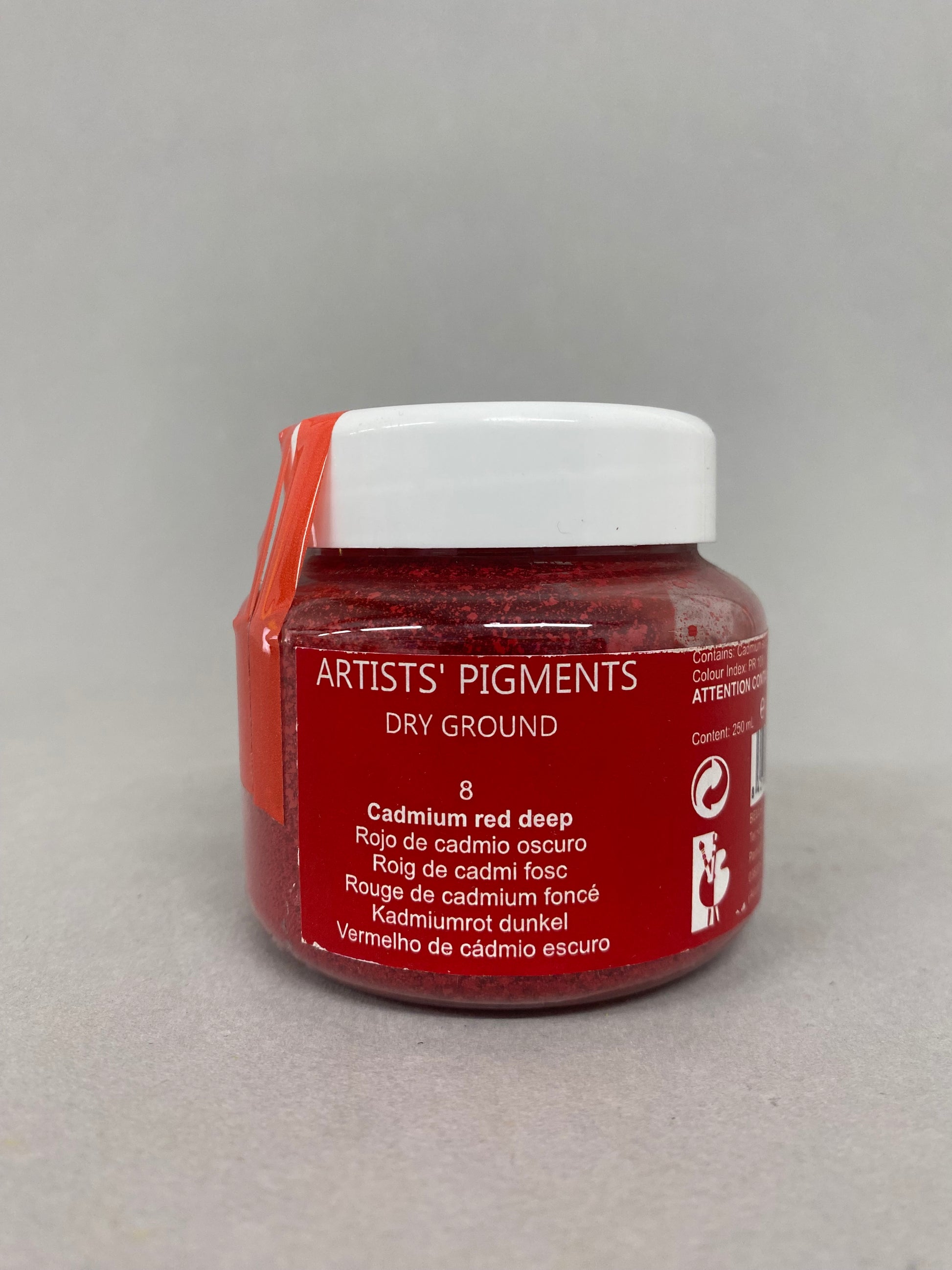 Red jar of artists' pigment on a gray background
