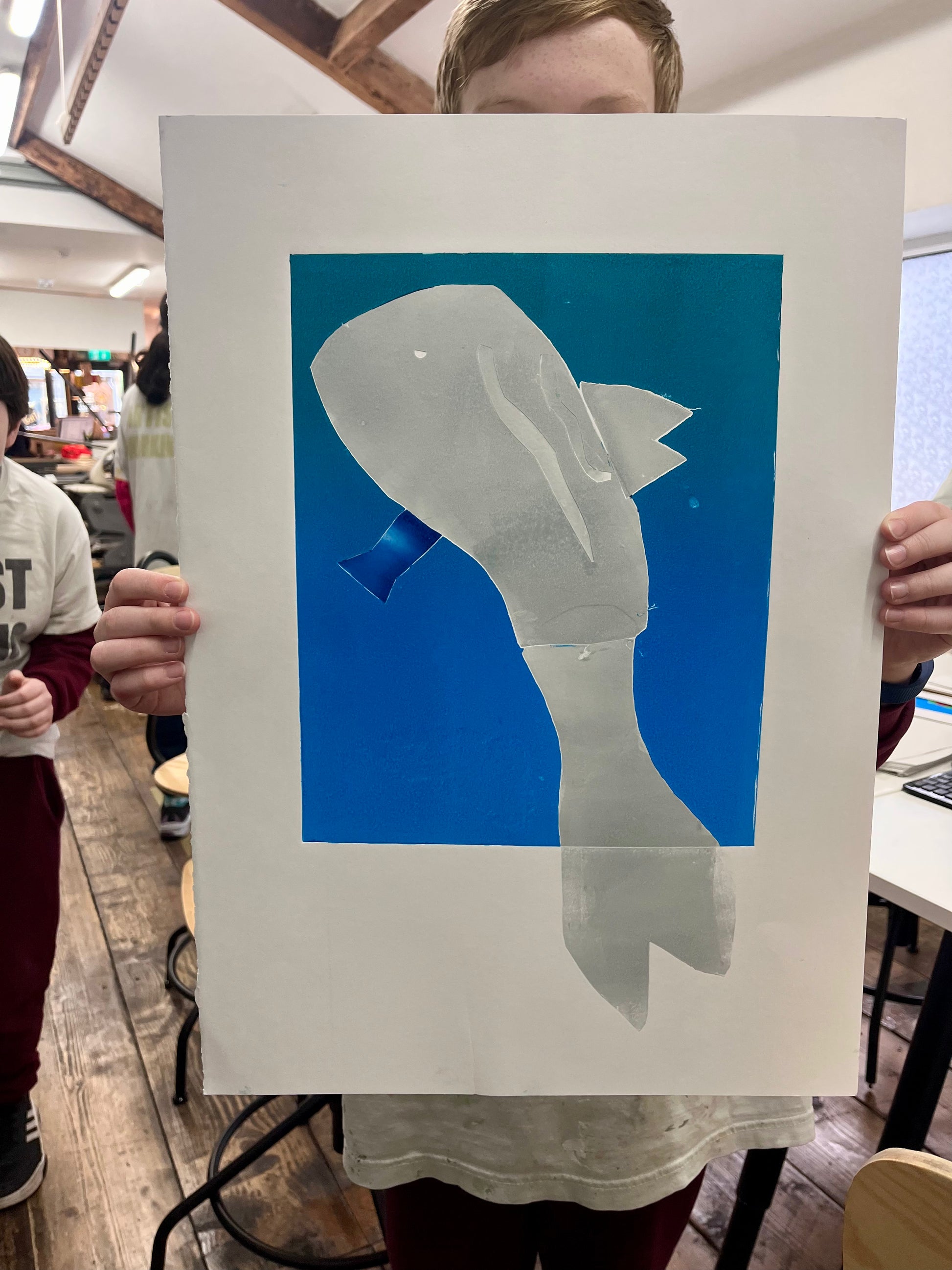 Child proudly holding his blue and white whale art print in our studio setting at Just Art It Galway 