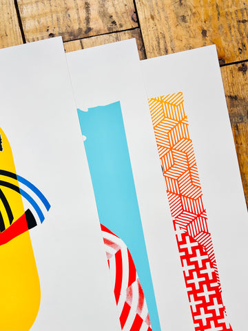 Three colorful abstract art prints on a wooden surface