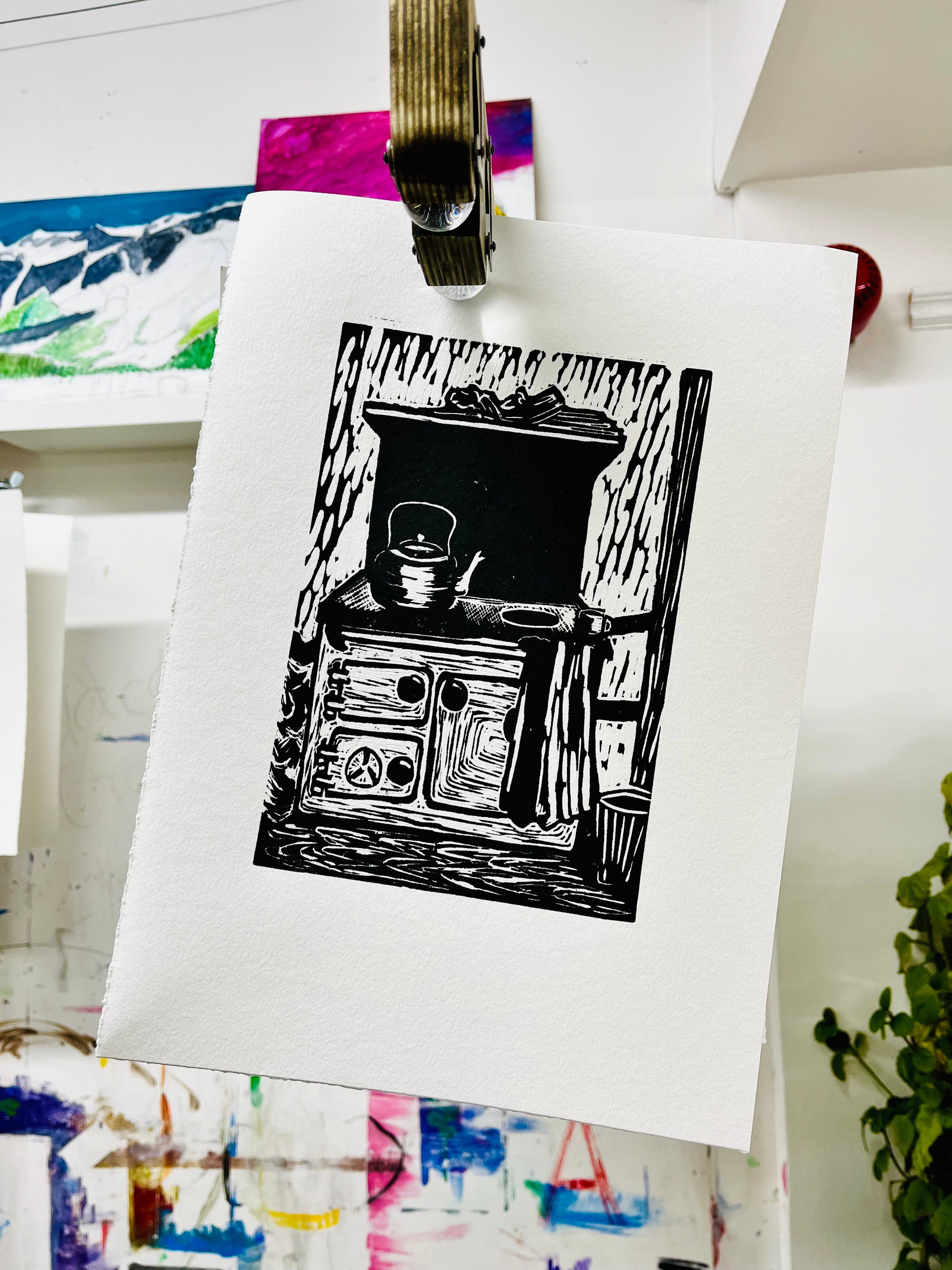 Black and white illustration of a stove on a white sheet of paper, pinned to a board with other artwork in the background.