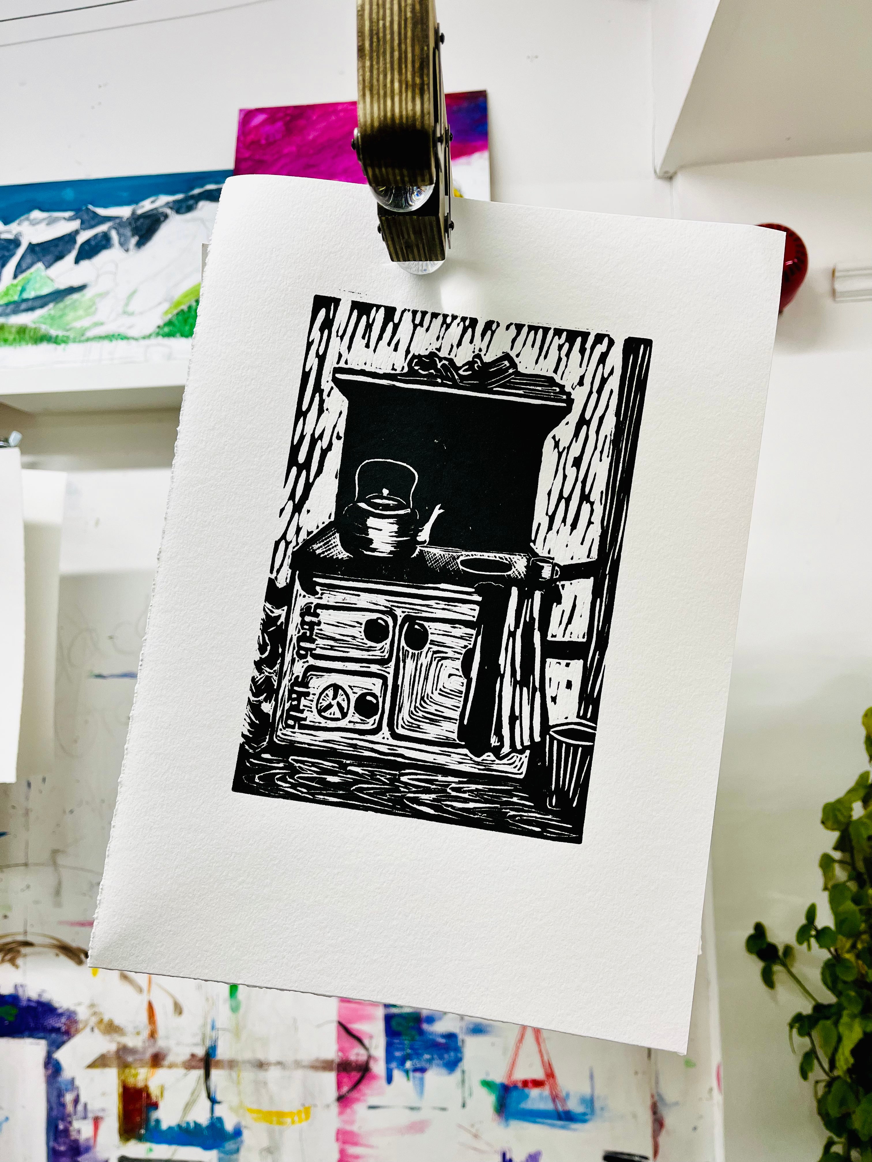 Black and white illustration of a stove on a white sheet of paper, pinned to a board with other artwork in the background.