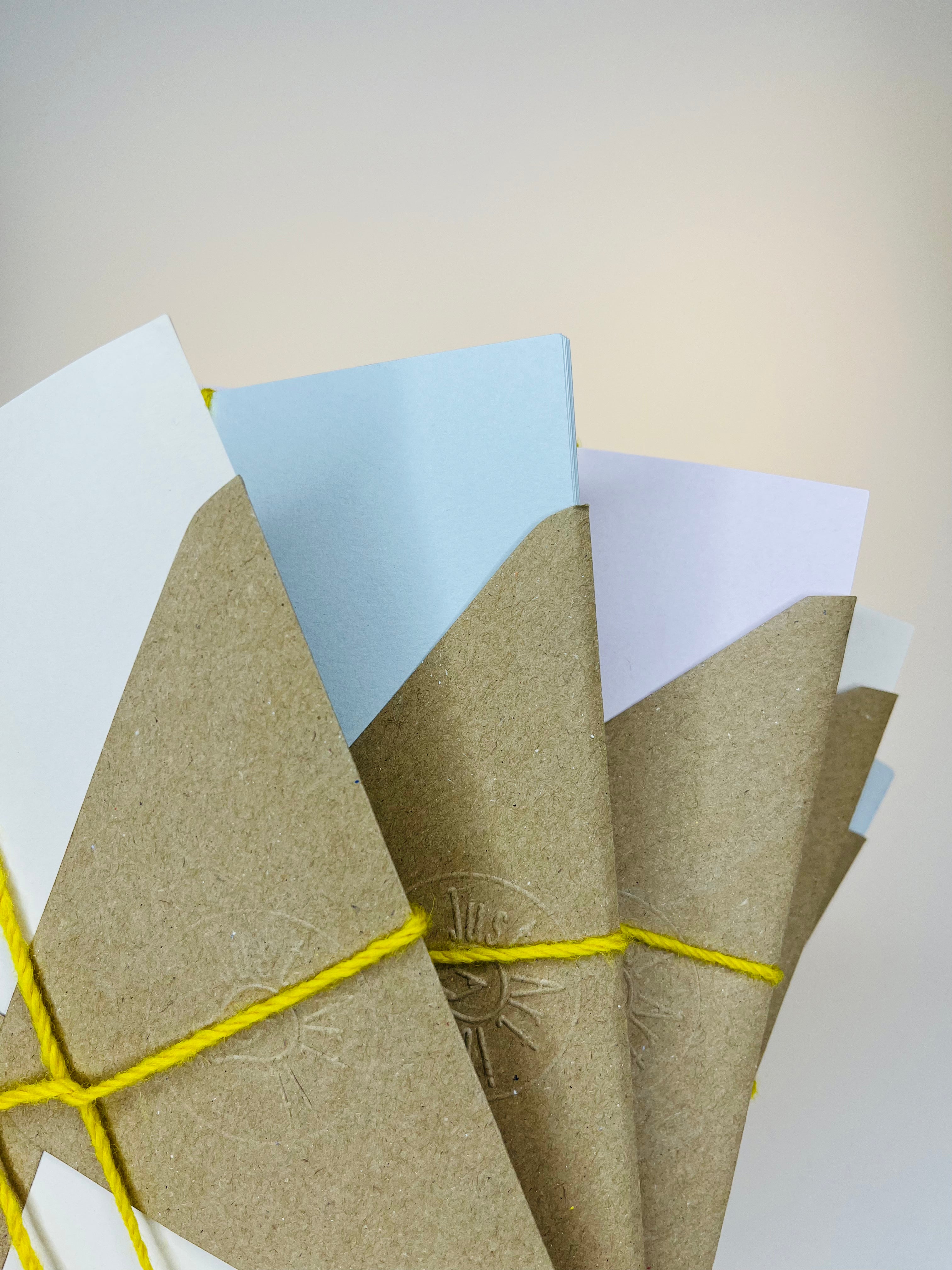 Bundles of colored paper in brown kraft paper packages tied with yellow twine.
