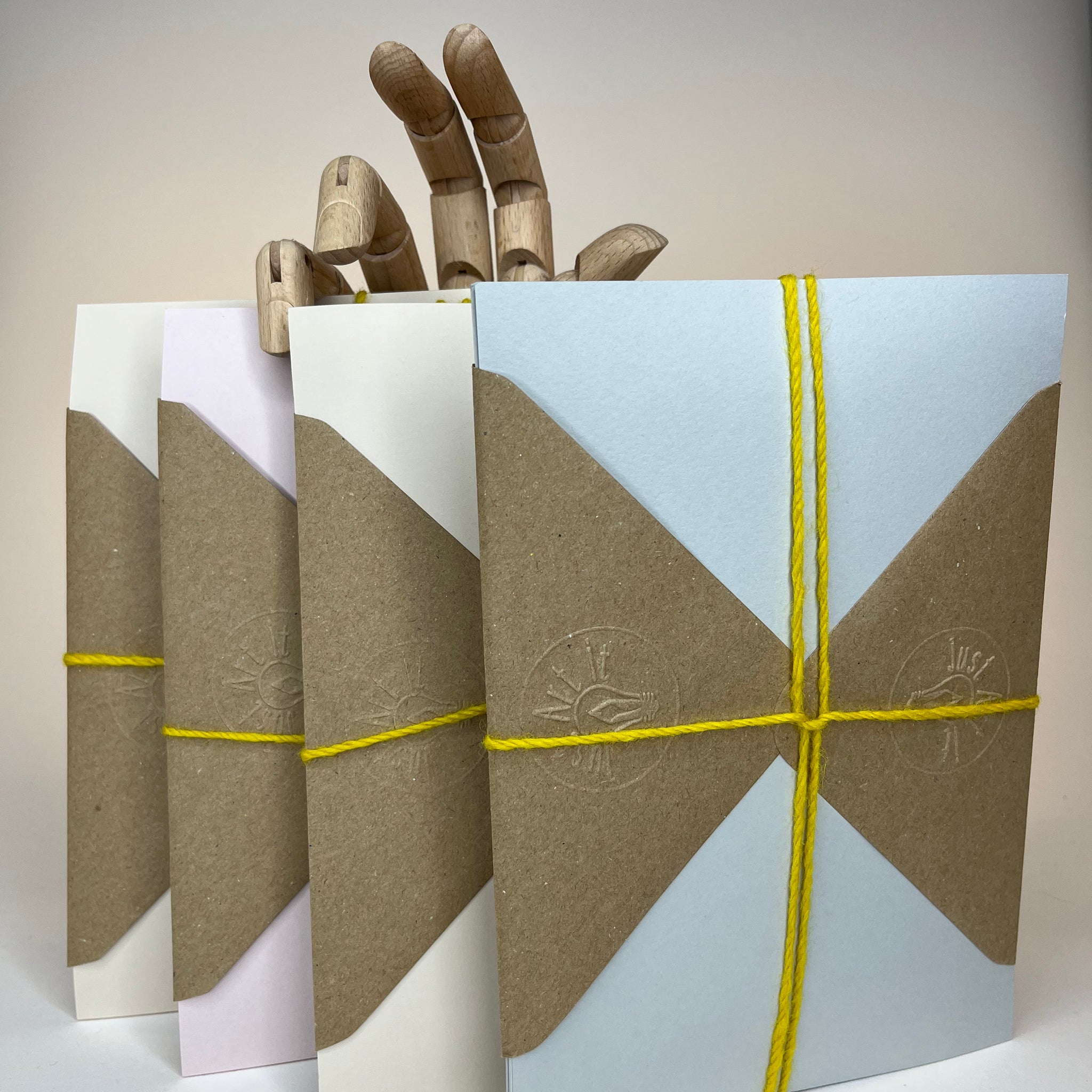 Four colorful envelopes with a hand made of wood.