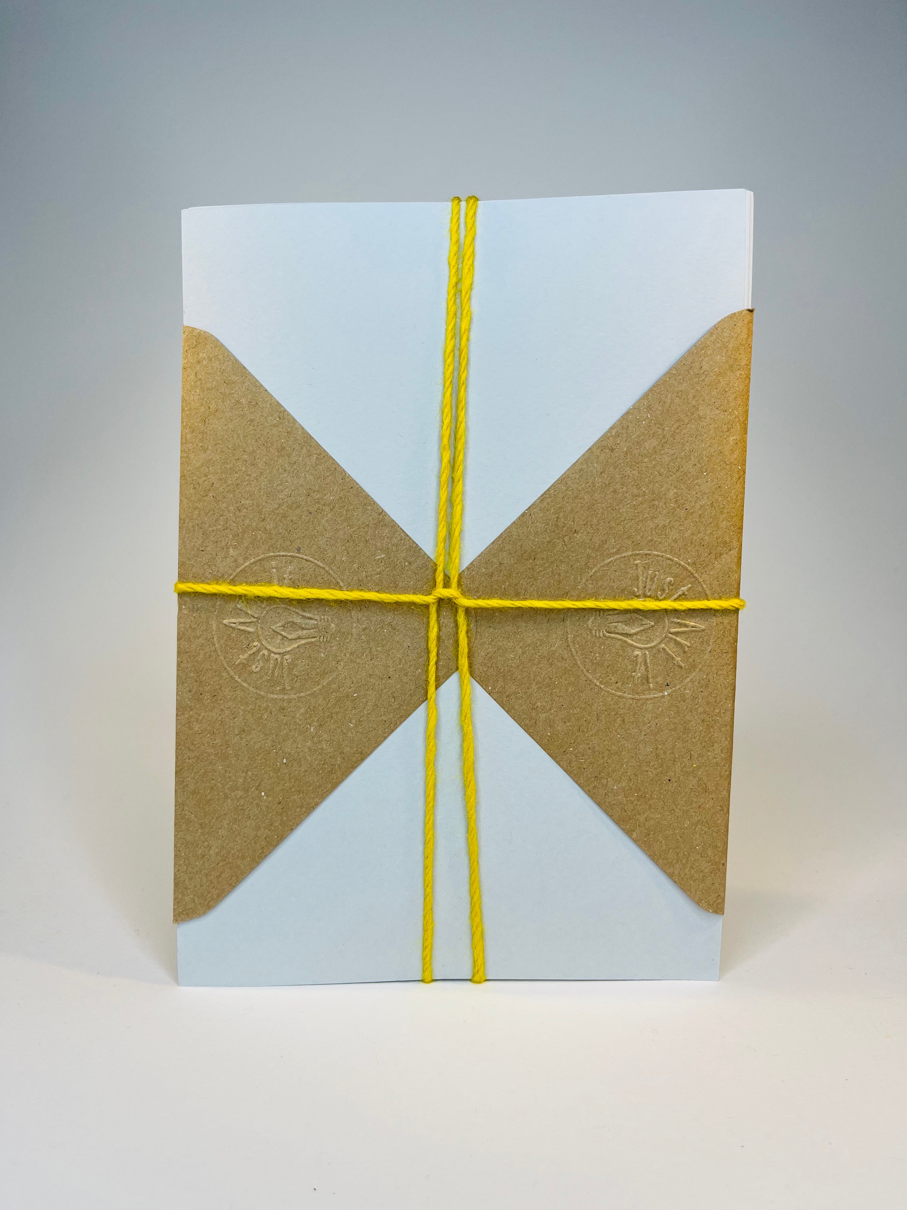 Square white box with brown triangular flaps, tied with yellow string.