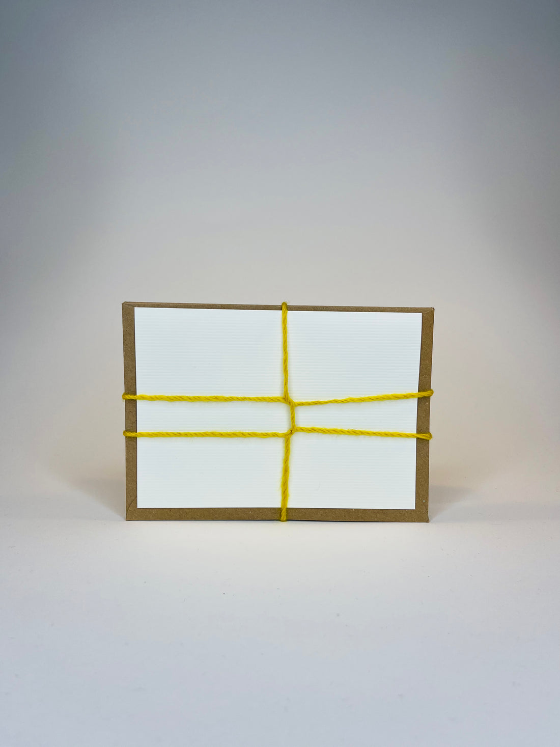 Wooden hand holding a stack of tied, colorful envelopes.