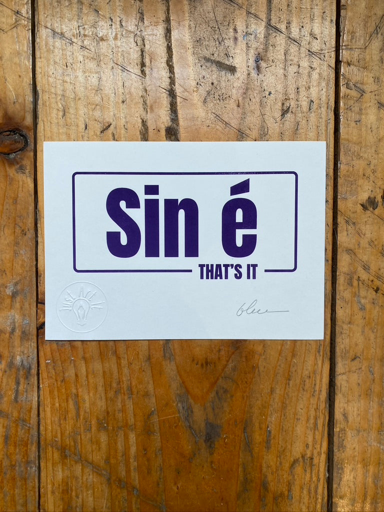 White card with 'Sin é THAT'S IT' text on a wooden surface