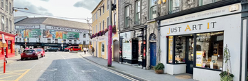 Street view of a building with a store named 'Just Art It' on a clear day.