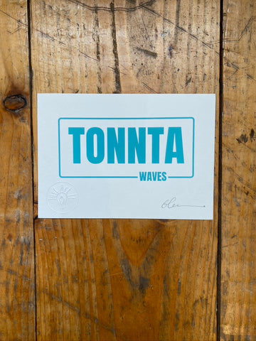 Screen print with 'TONNTA WAVES' text on a wooden floor