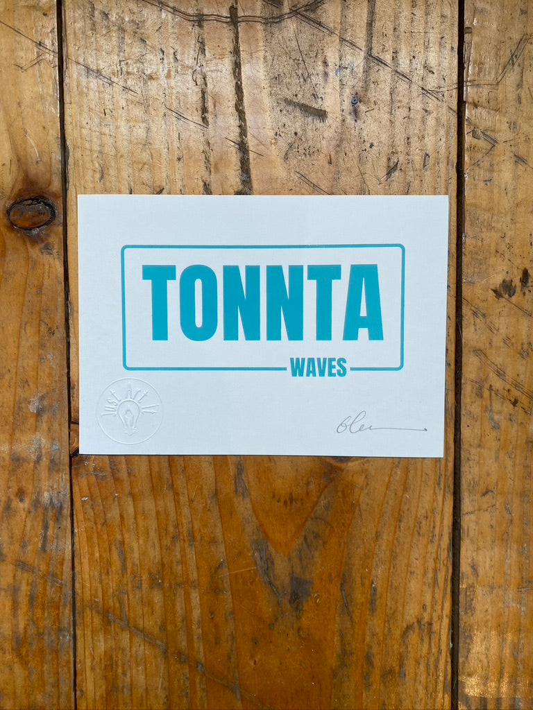Screen print with 'TONNTA WAVES' text on a wooden floor