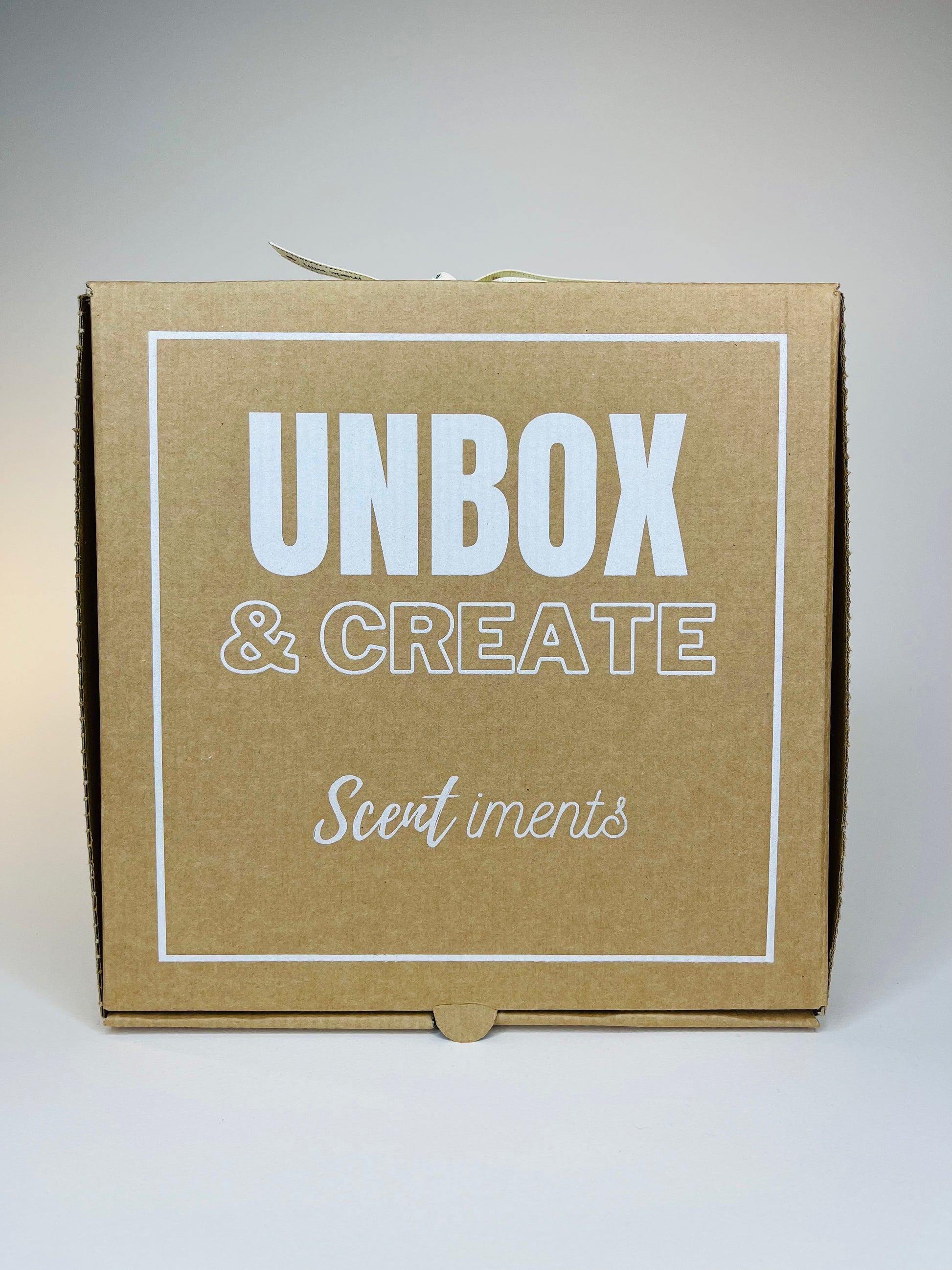 Brown cardboard box with "Unbox & Create" and "Scentiments" in white font.