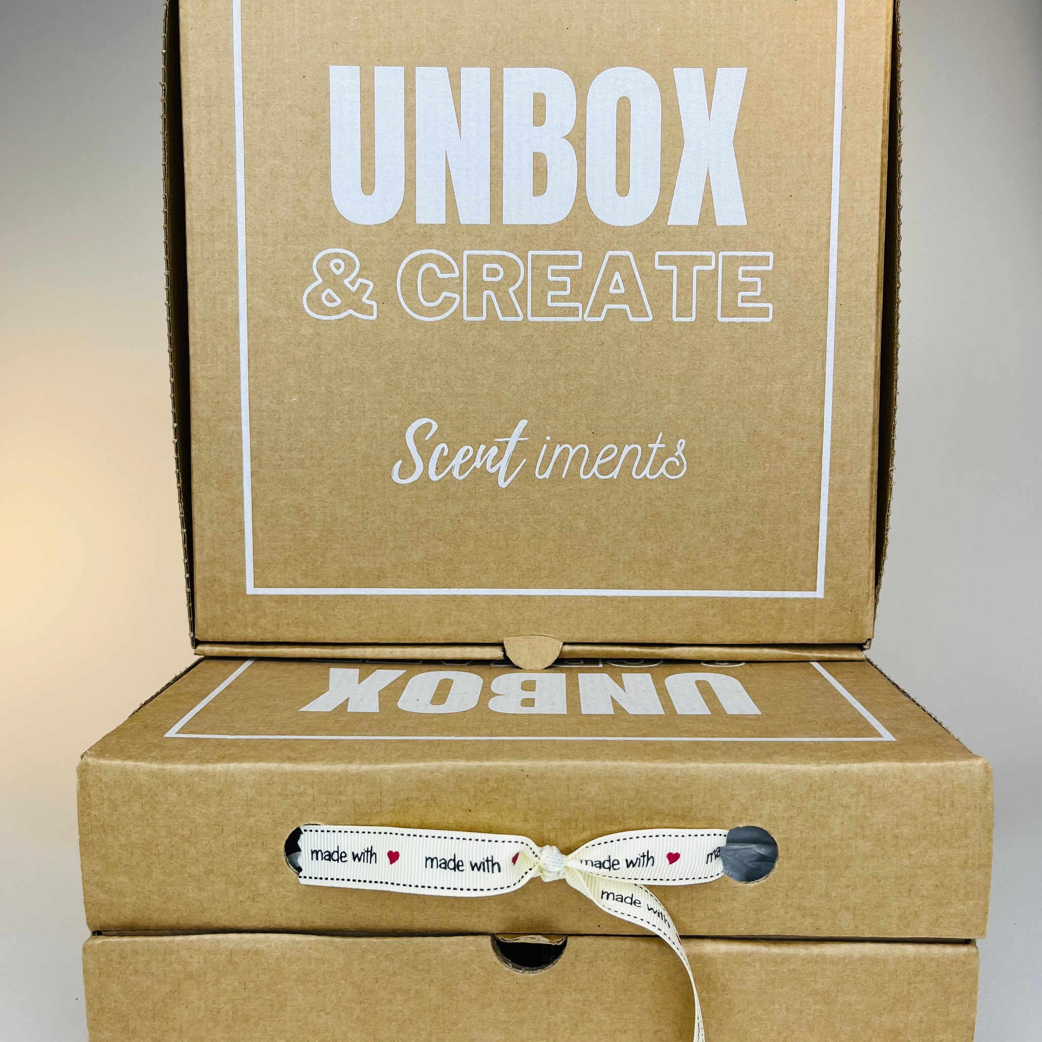 A stack of three brown cardboard boxes with white lettering and a ribbon tied around the middle box.