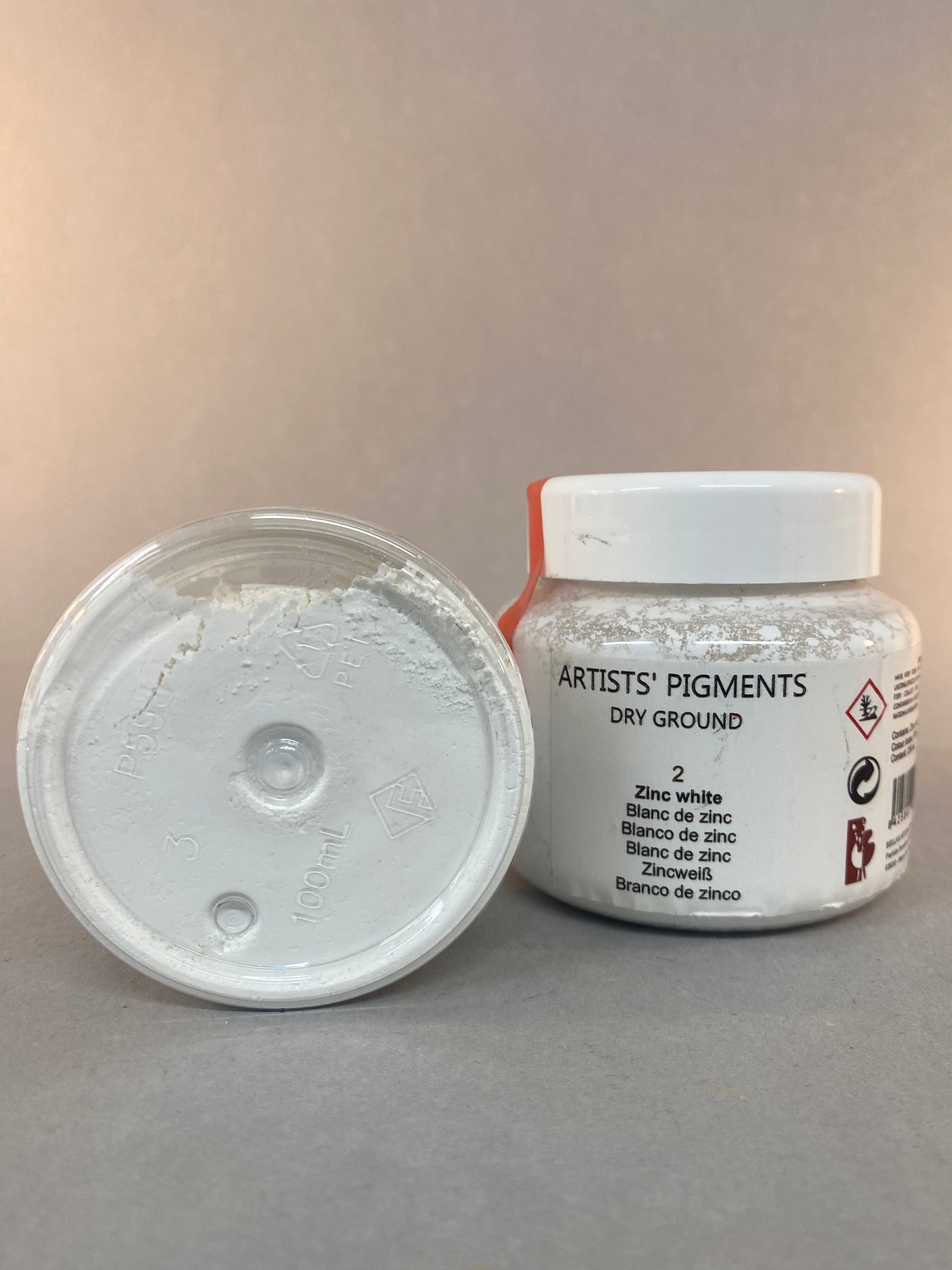 Small container of artists' pigment on a gray background