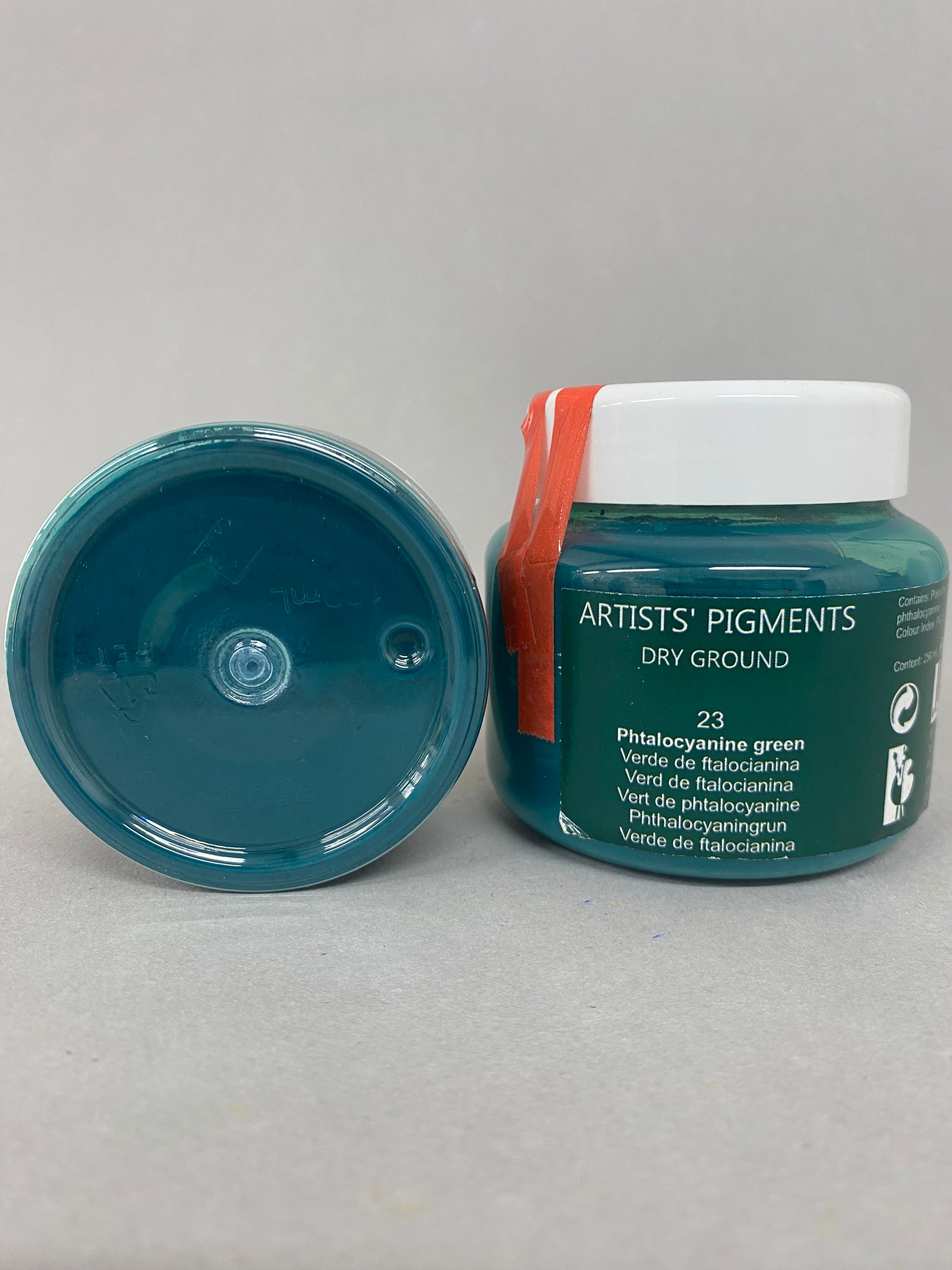 Artists' pigments container with open lid on a gray background