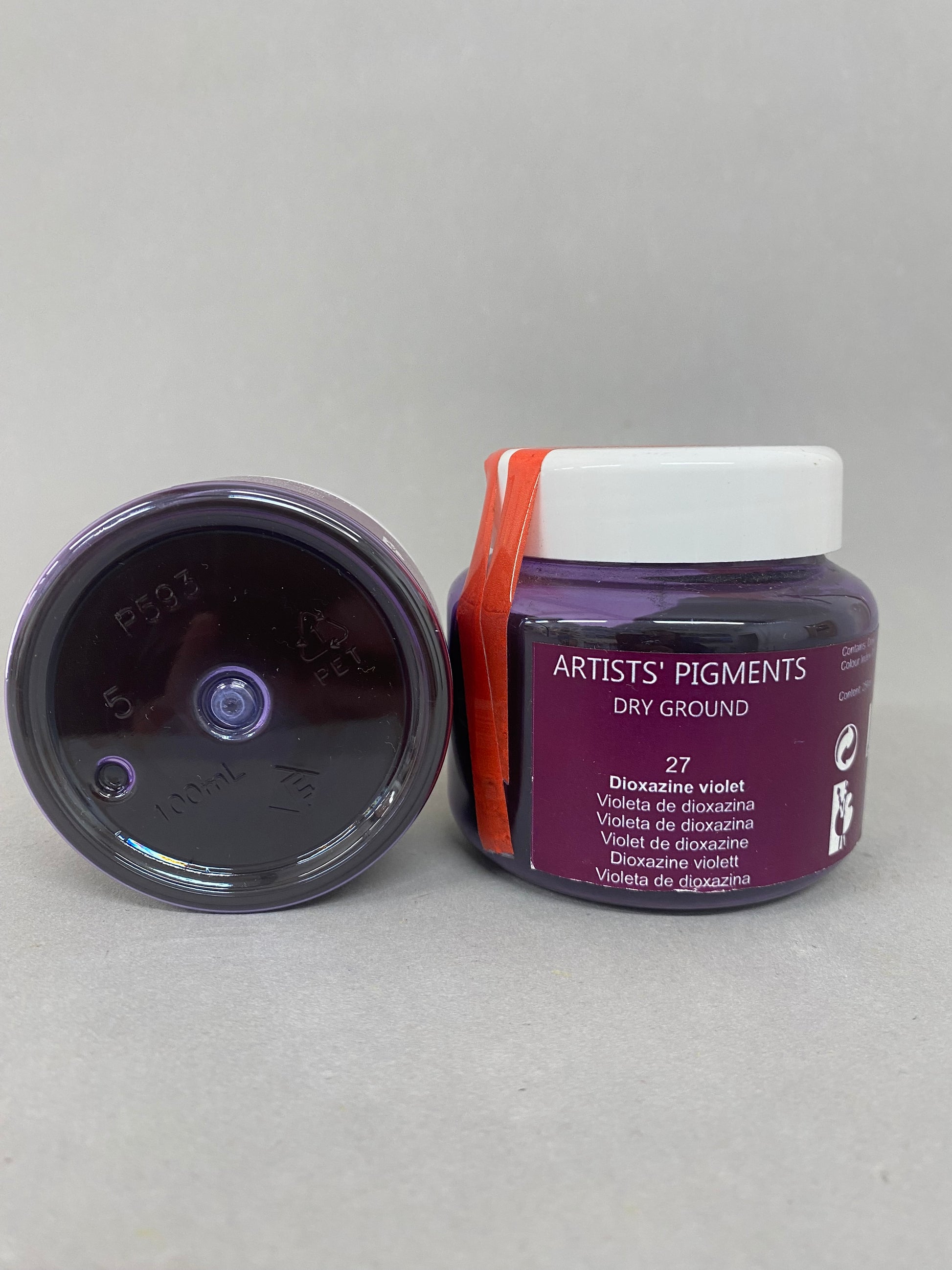 Two containers of artist pigments on a gray background