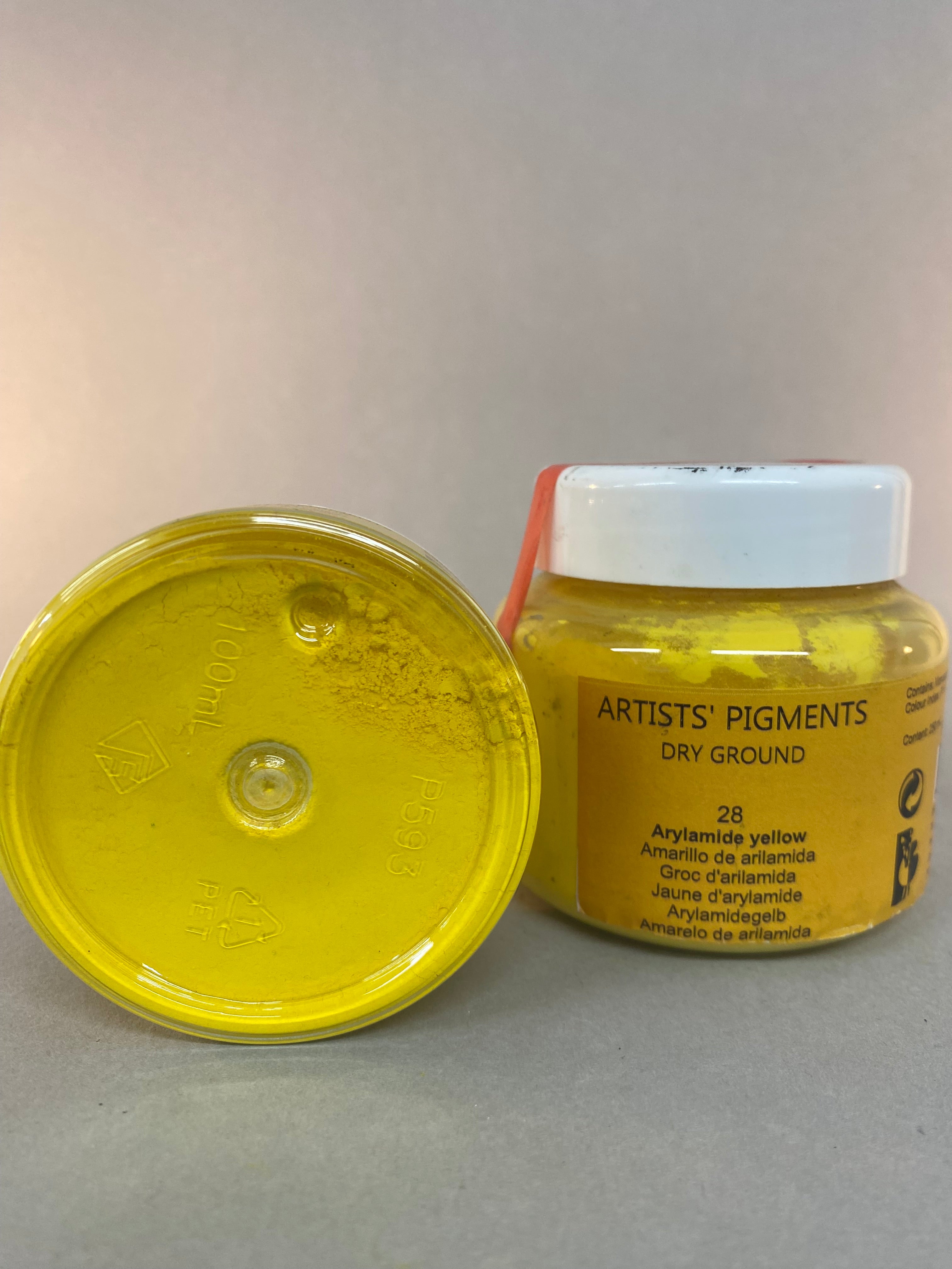 Yellow container of artists' pigment on a gray background