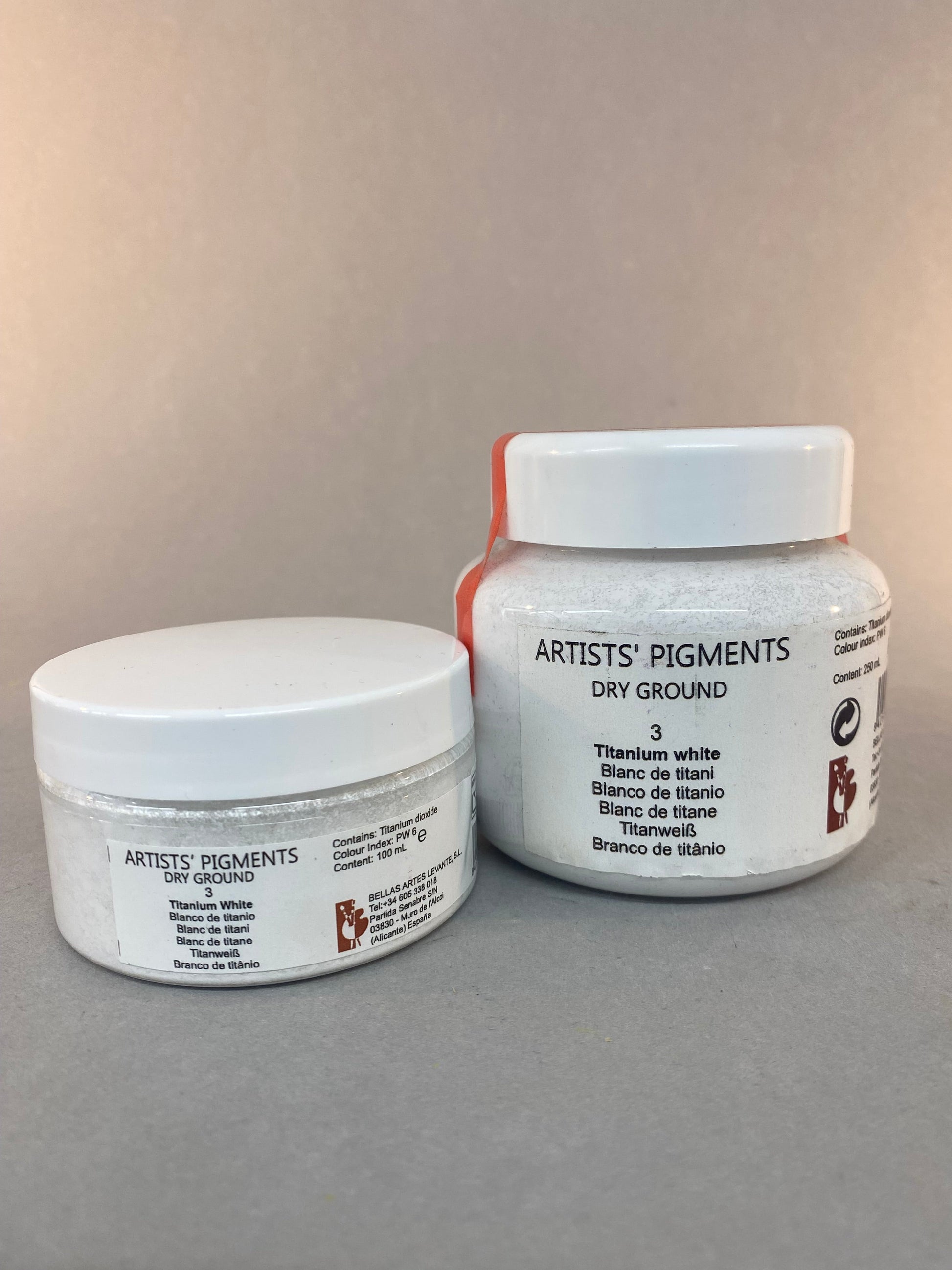 Two containers of 'Artists' Pigments' on a gray background